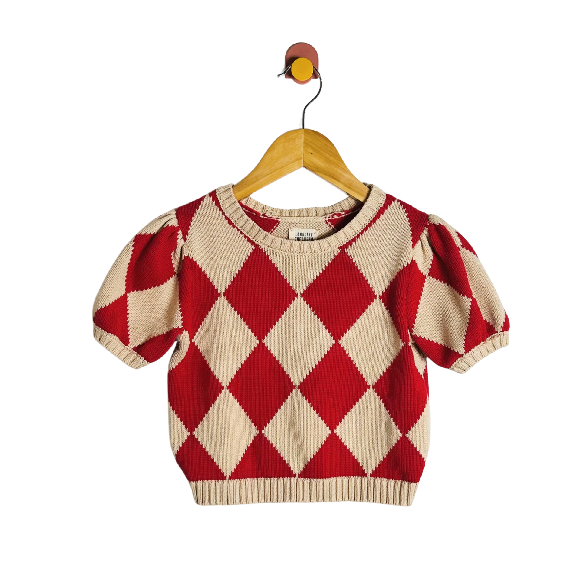 Red and beige argyle patterned sweater on a hanger against a white background
