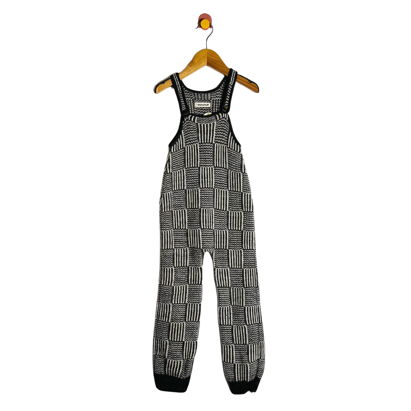 Black and white checkered overalls on a hanger against a white background