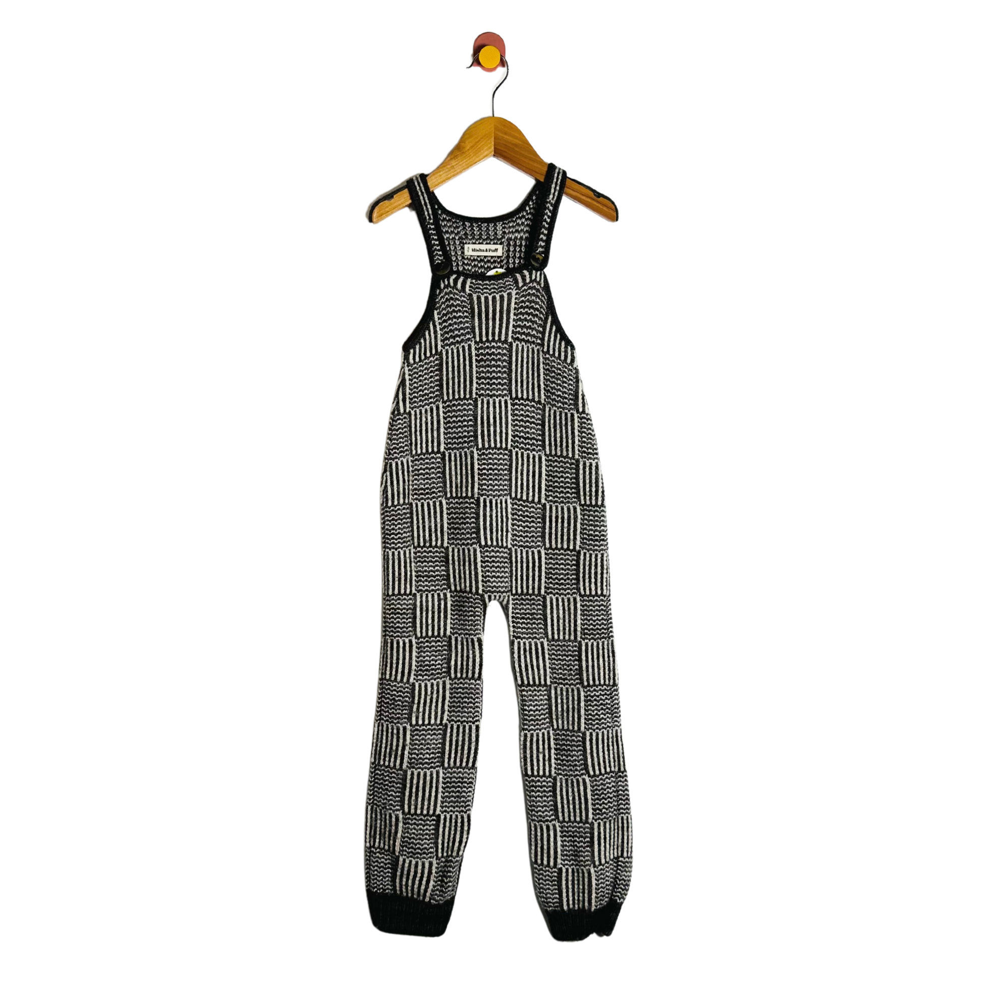 Black and white checkered overalls on a hanger against a white background