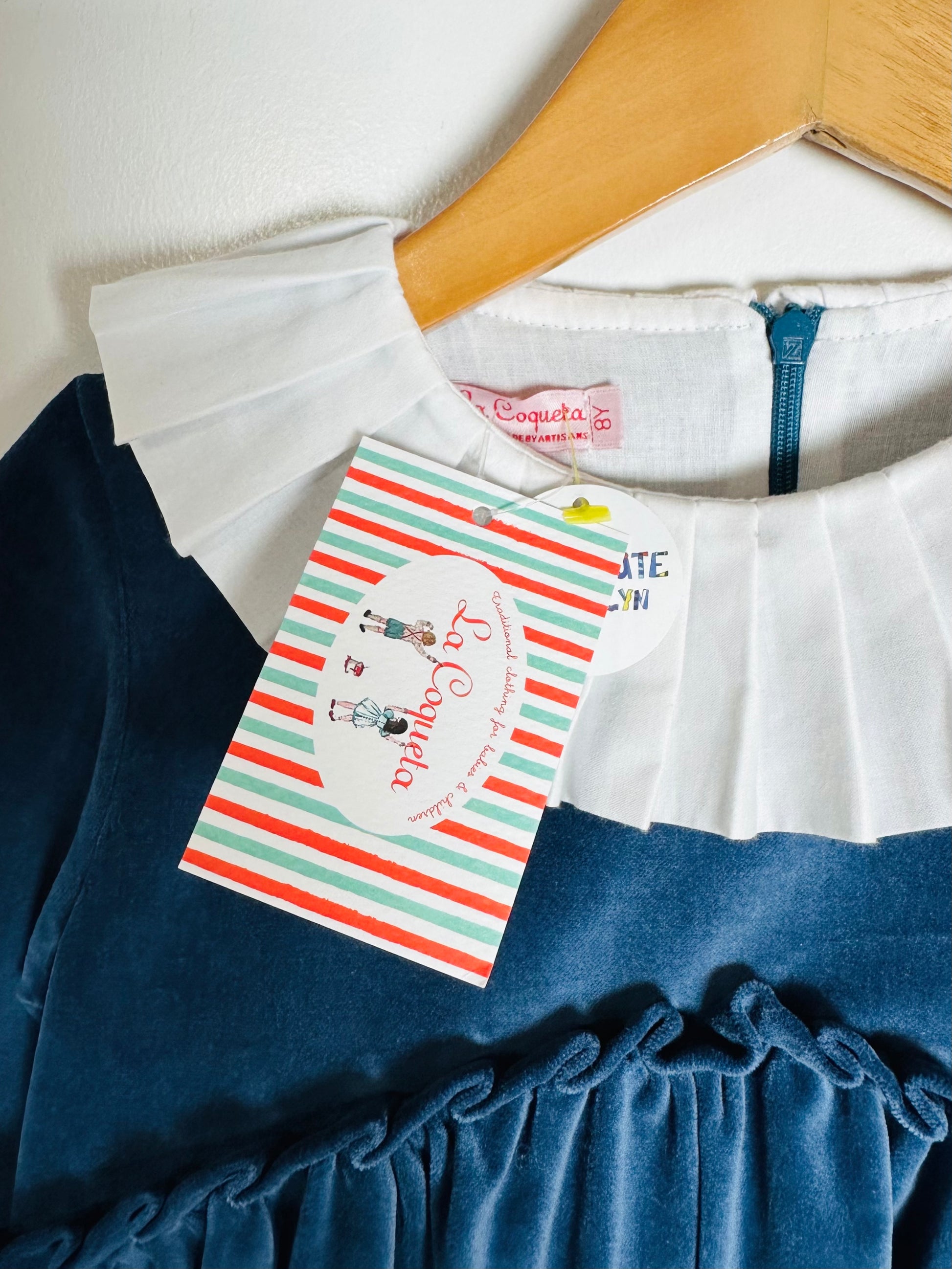 Children's dress with a hanger and brand tag on a white background