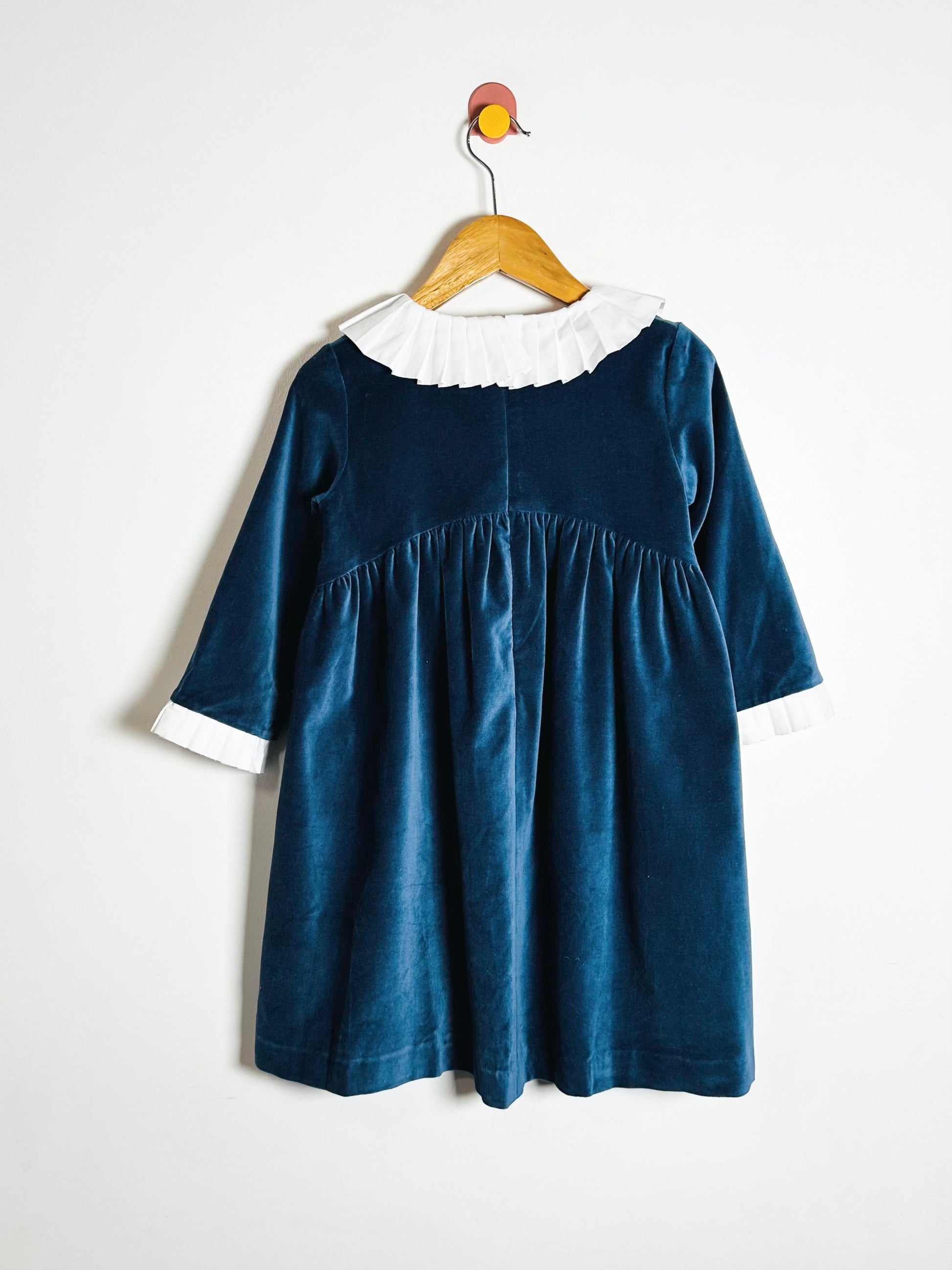 Blue dress with white collar on a hanger against a white background