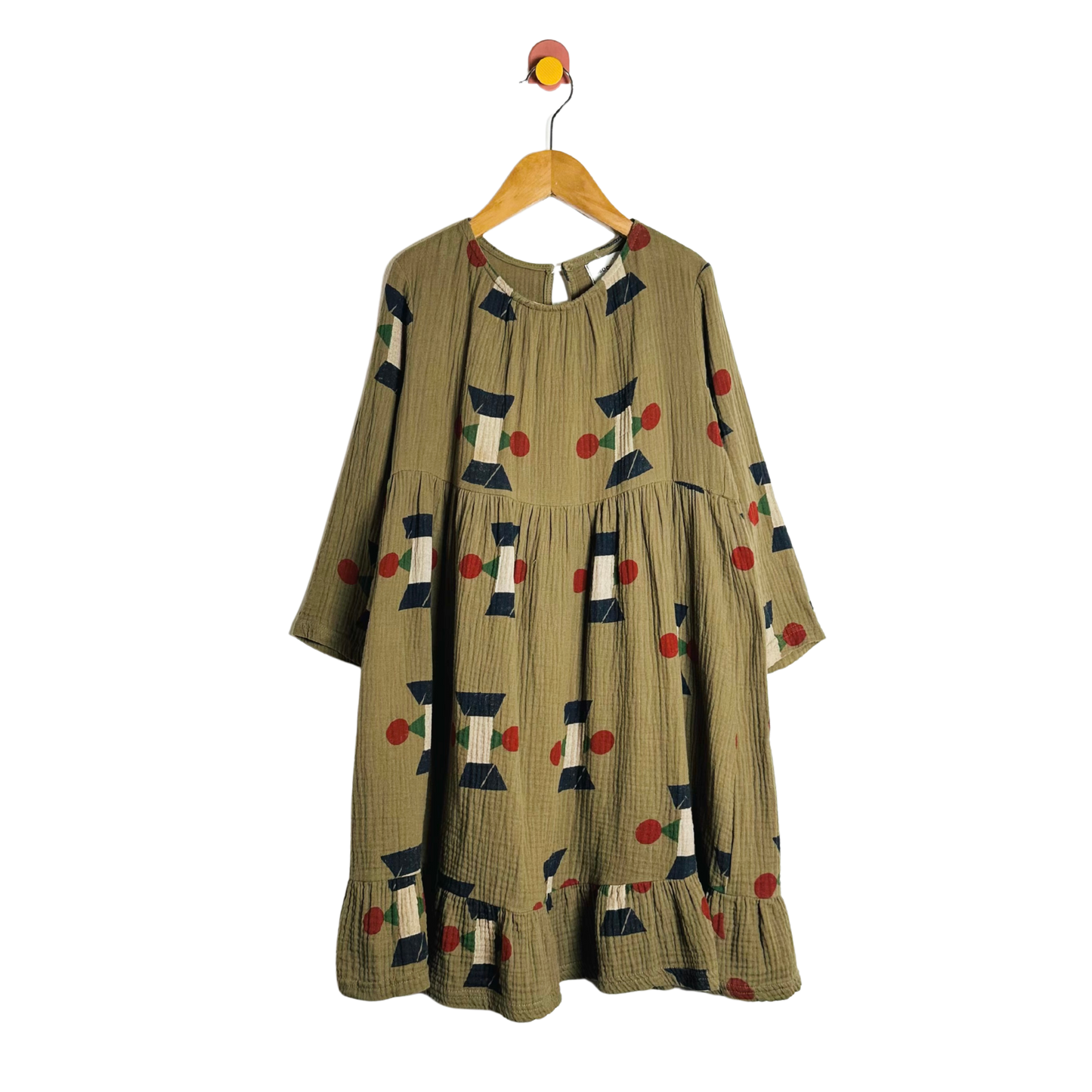 Green dress with geometric pattern on a hanger against a white background