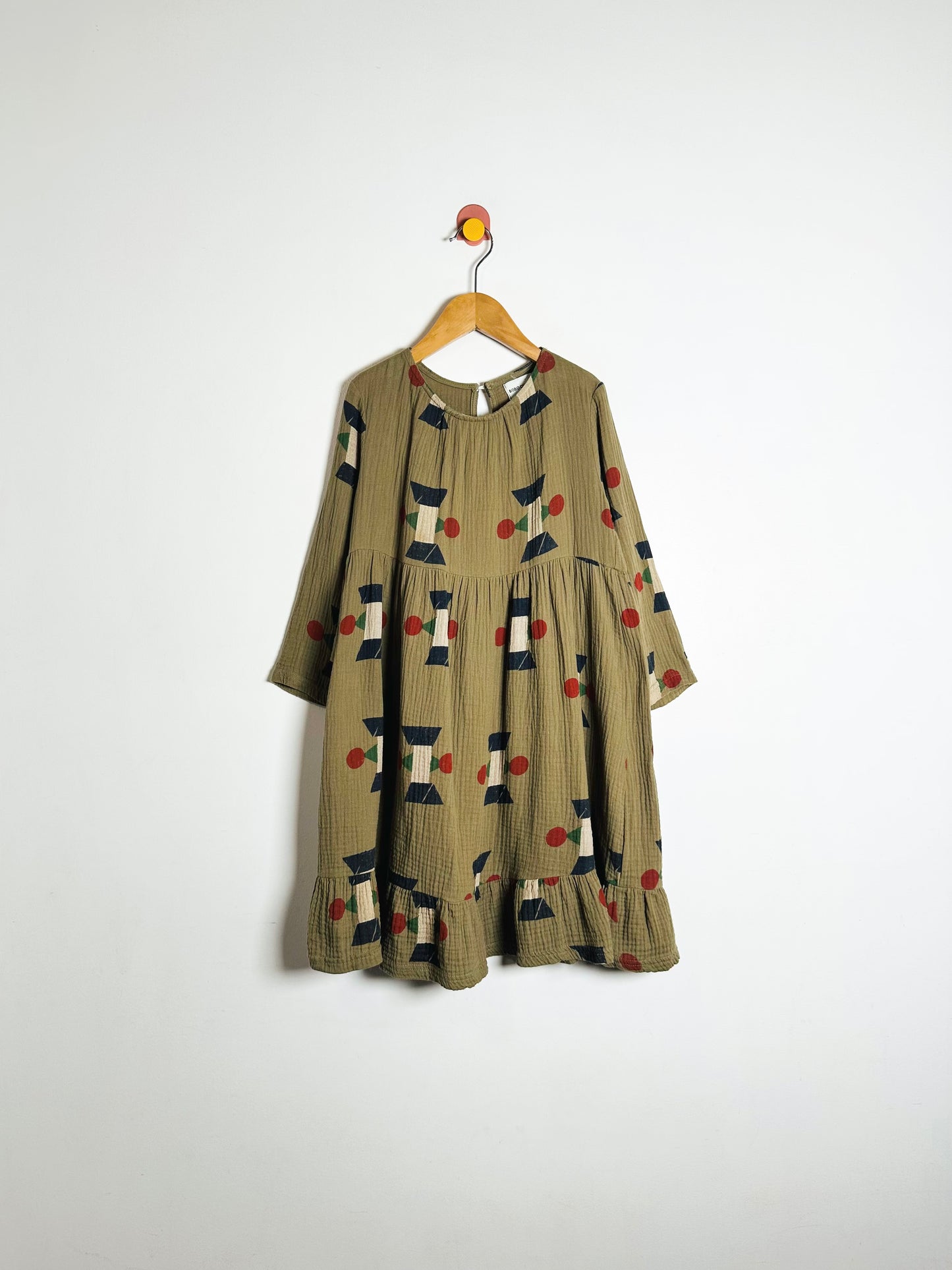 Green dress with pattern on a hanger against a white background