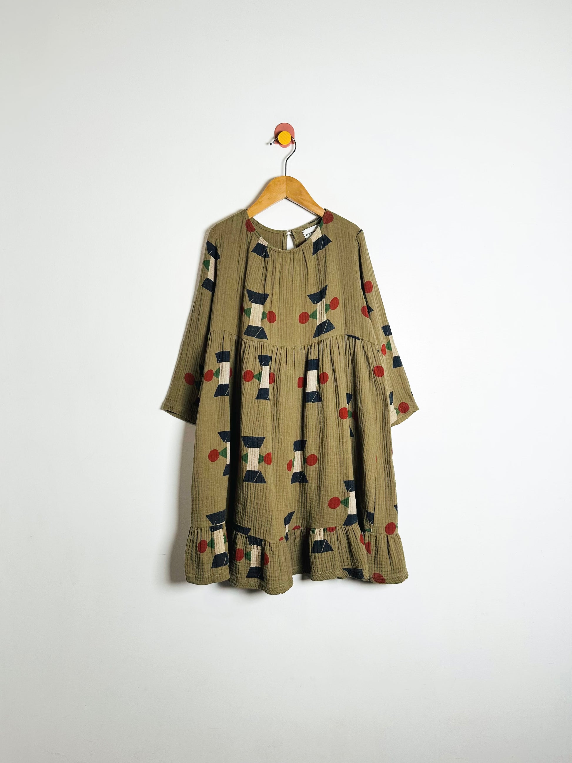 Green dress with pattern on a hanger against a white background