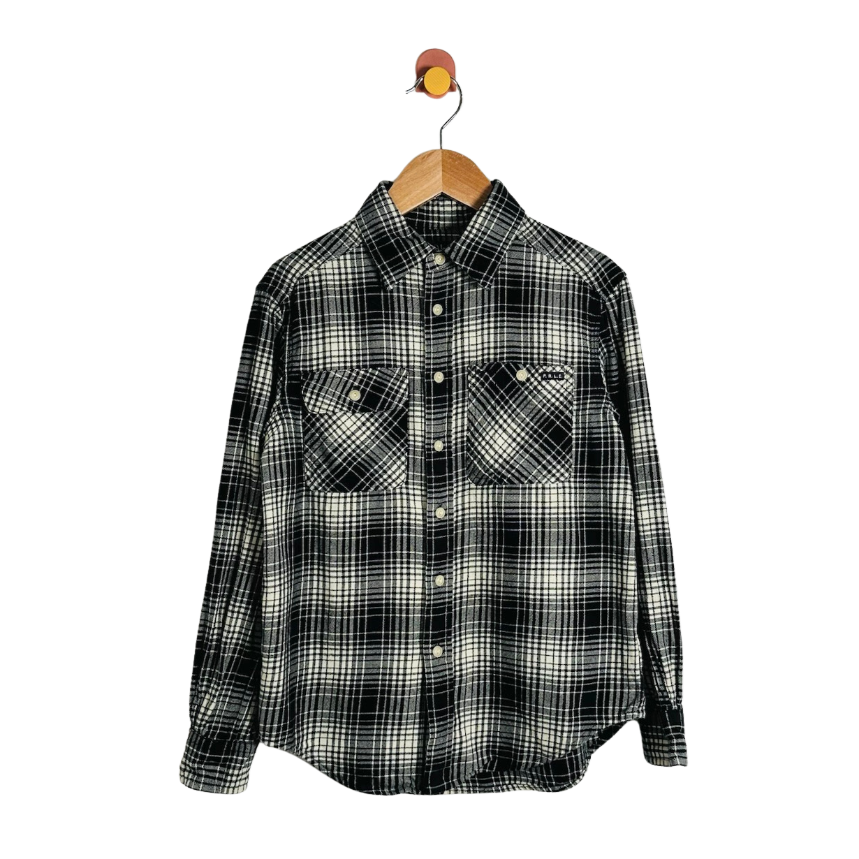 A long-sleeve plaid button-up shirt in black and off-white, hanging on a wooden hanger with a small bird-shaped hook against a plain white background.