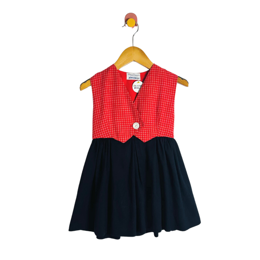 Children's dress with red checkered top and navy skirt on a hanger against a white background