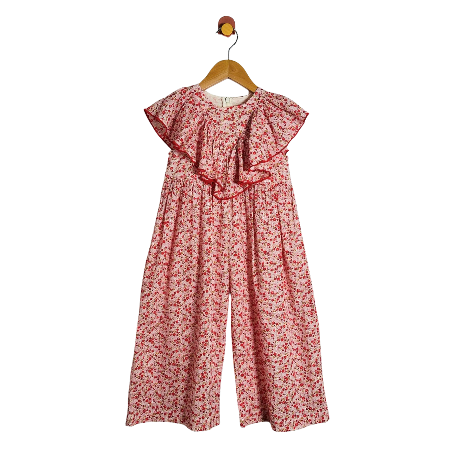 A children's floral jumpsuit with wide legs and ruffled cap sleeves, hanging on a wooden hanger against a plain white background.
