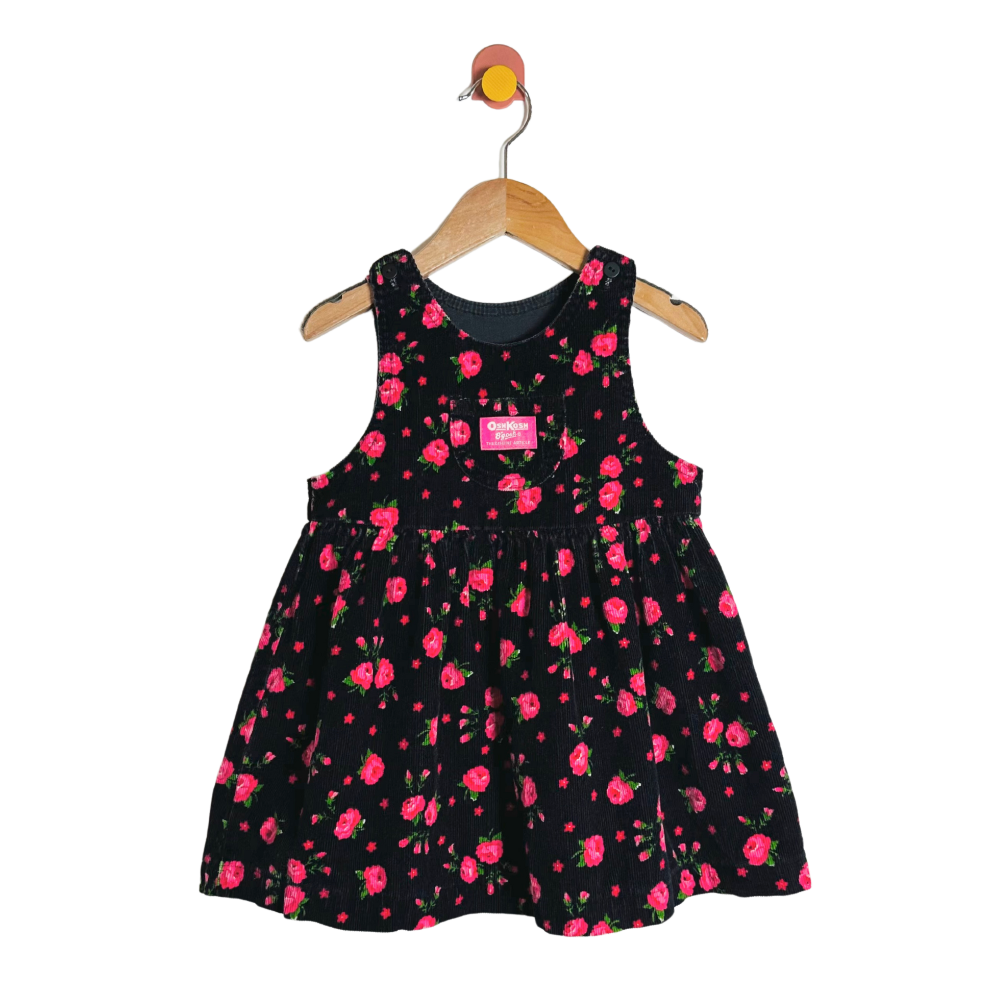 Black dress with pink floral pattern on a hanger against a white background
