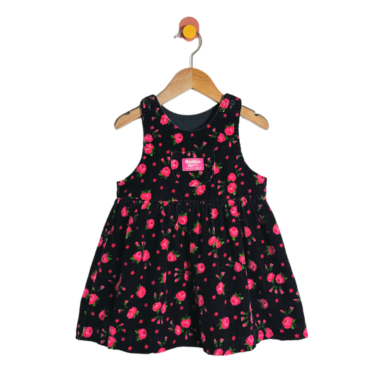 Black dress with pink floral pattern on a hanger against a white background