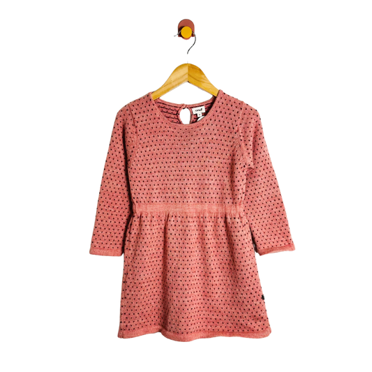 Pink polka dot dress on a hanger against a white background