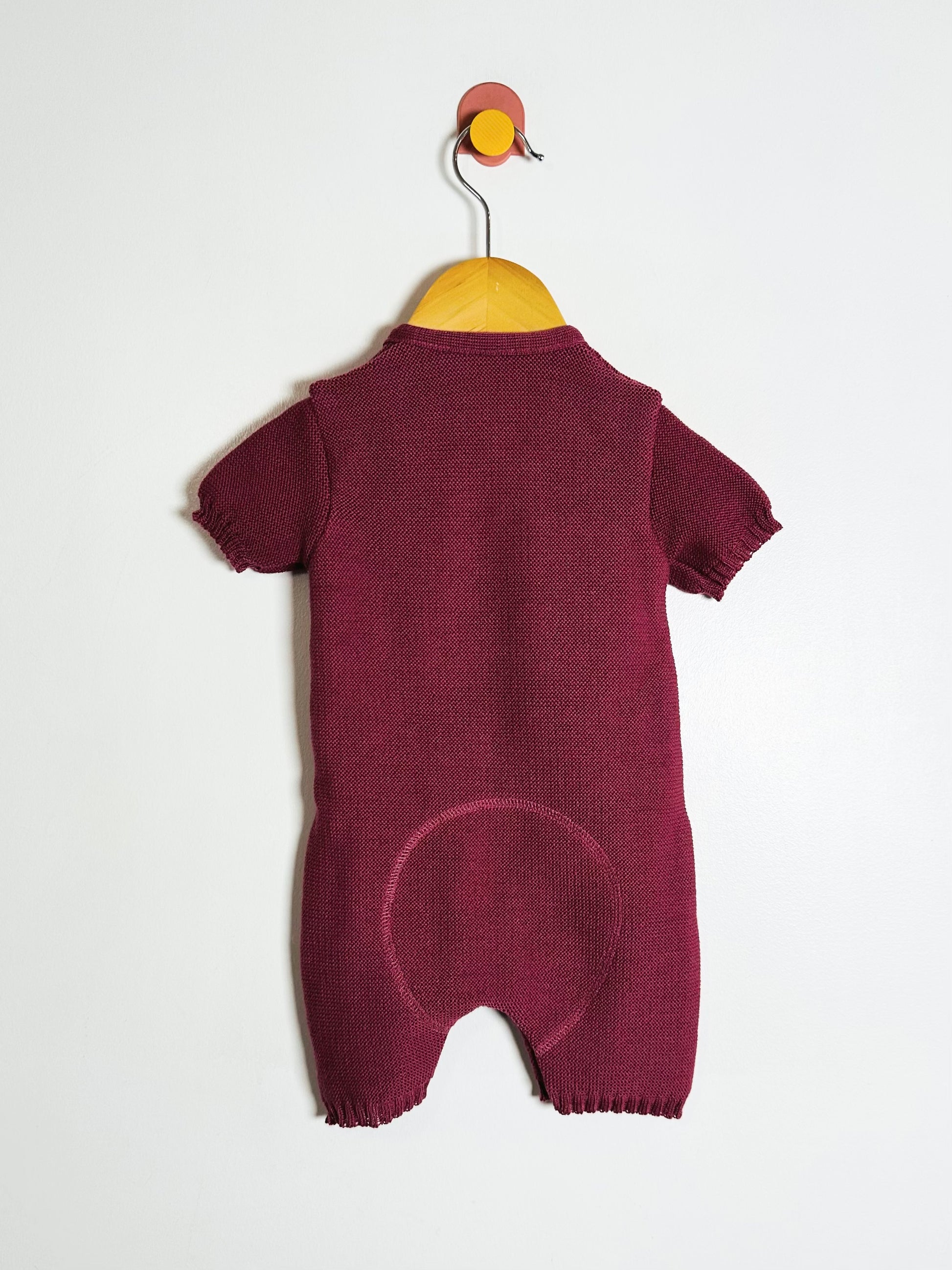 Maroon baby romper on a hanger against a white background