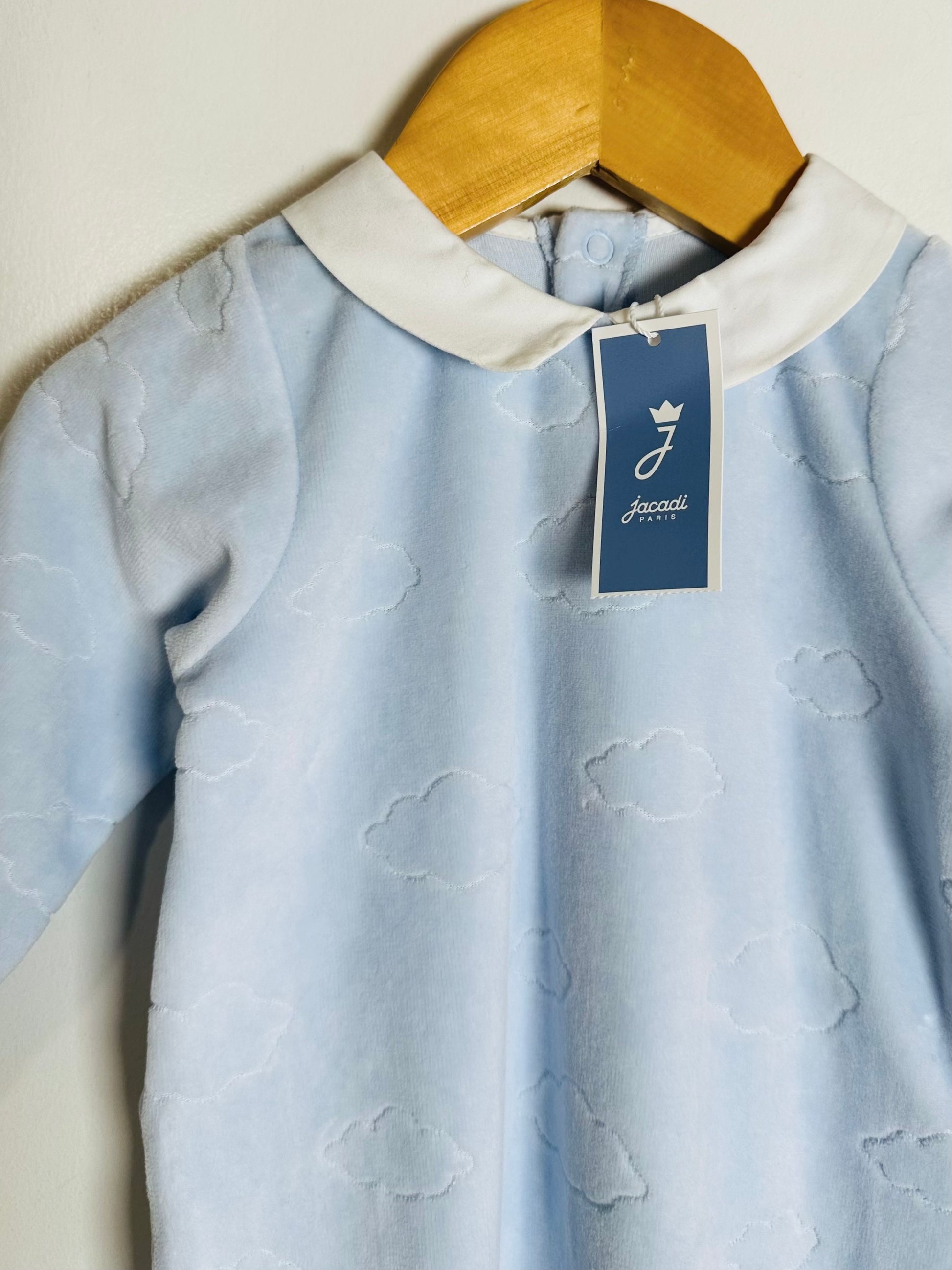Light blue baby outfit with white collar on a hanger, featuring a brand tag.