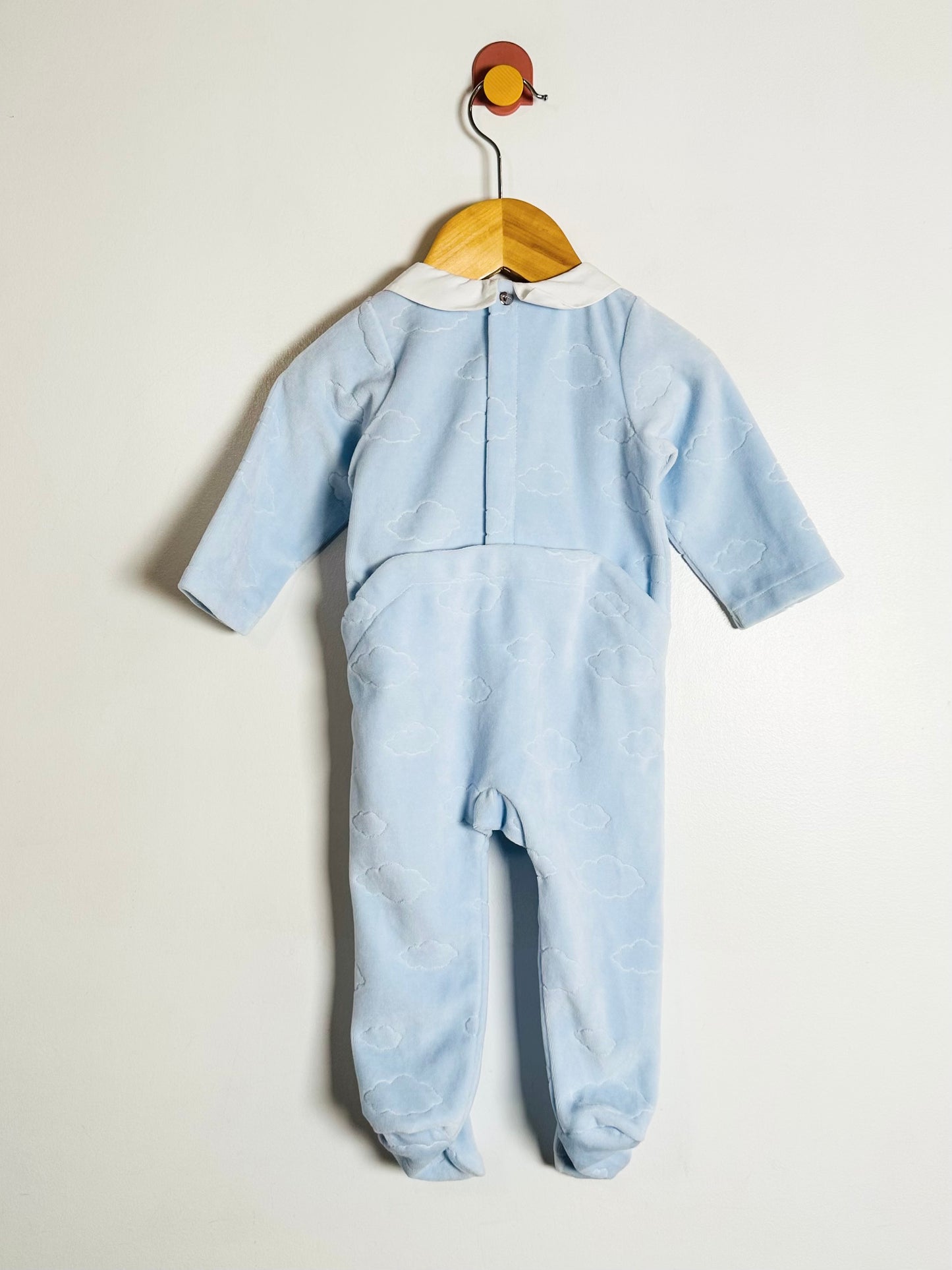 Light blue baby onesie on a wooden hanger against a white background
