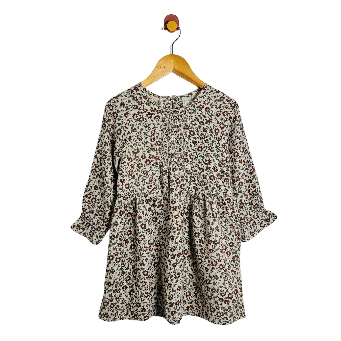 A long-sleeve babydoll dress with a brown and beige floral print pattern, hanging on a wooden hanger against a plain white background.