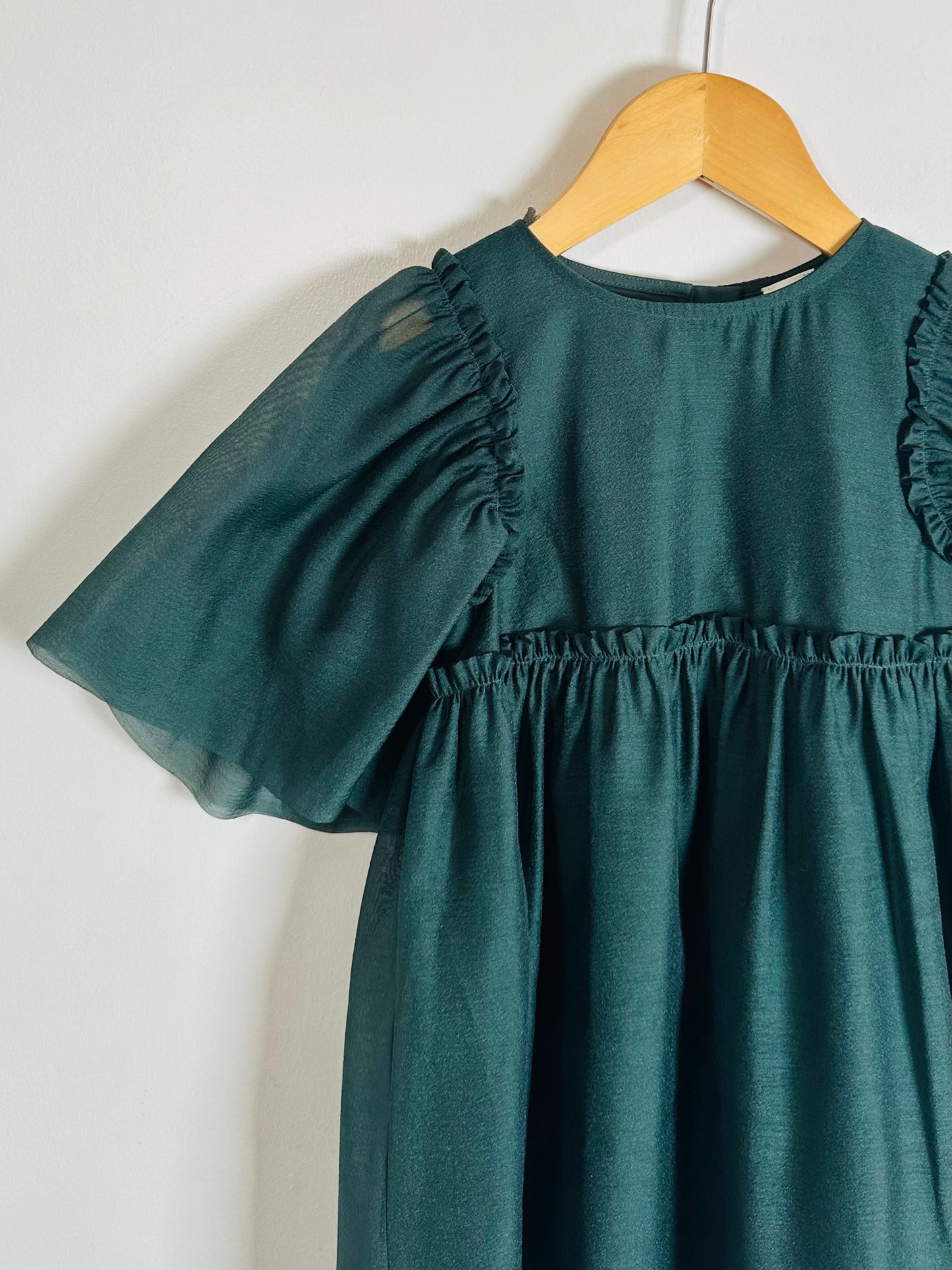 Green dress on a wooden hanger against a white background