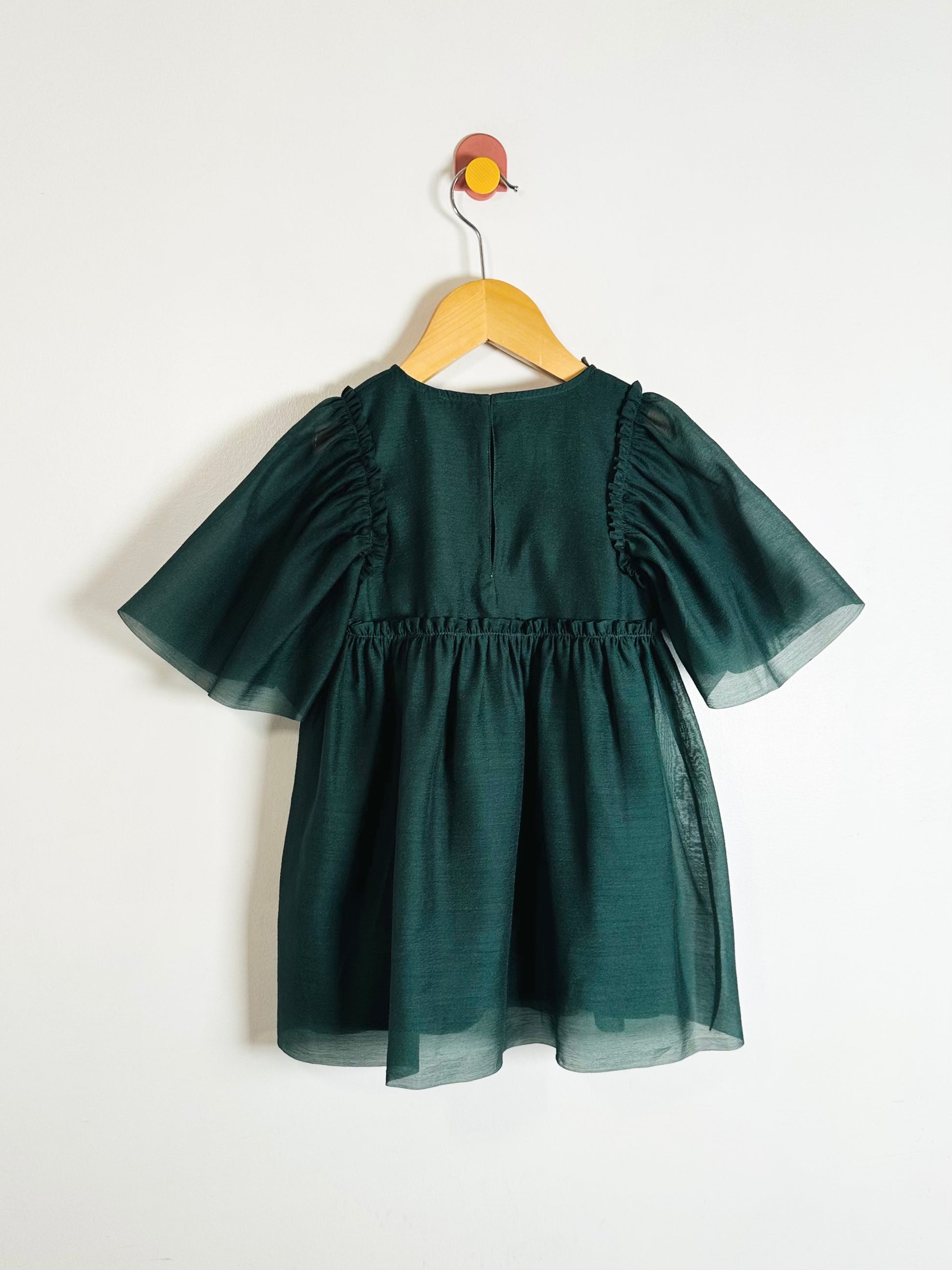Green dress on a hanger against a white background