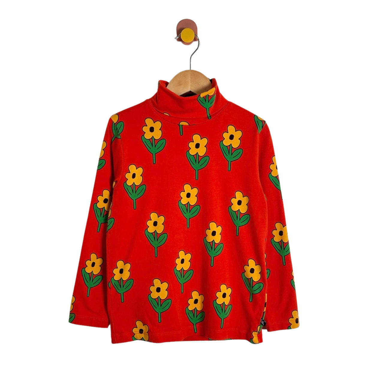 A red long-sleeve mock-neck top with an all-over yellow flower and green leaf pattern, hanging on a wooden hanger against a plain white background.