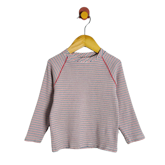 A long-sleeve raglan top with a fine red, blue, and white stripe pattern, hanging on a wooden hanger against a plain white background.