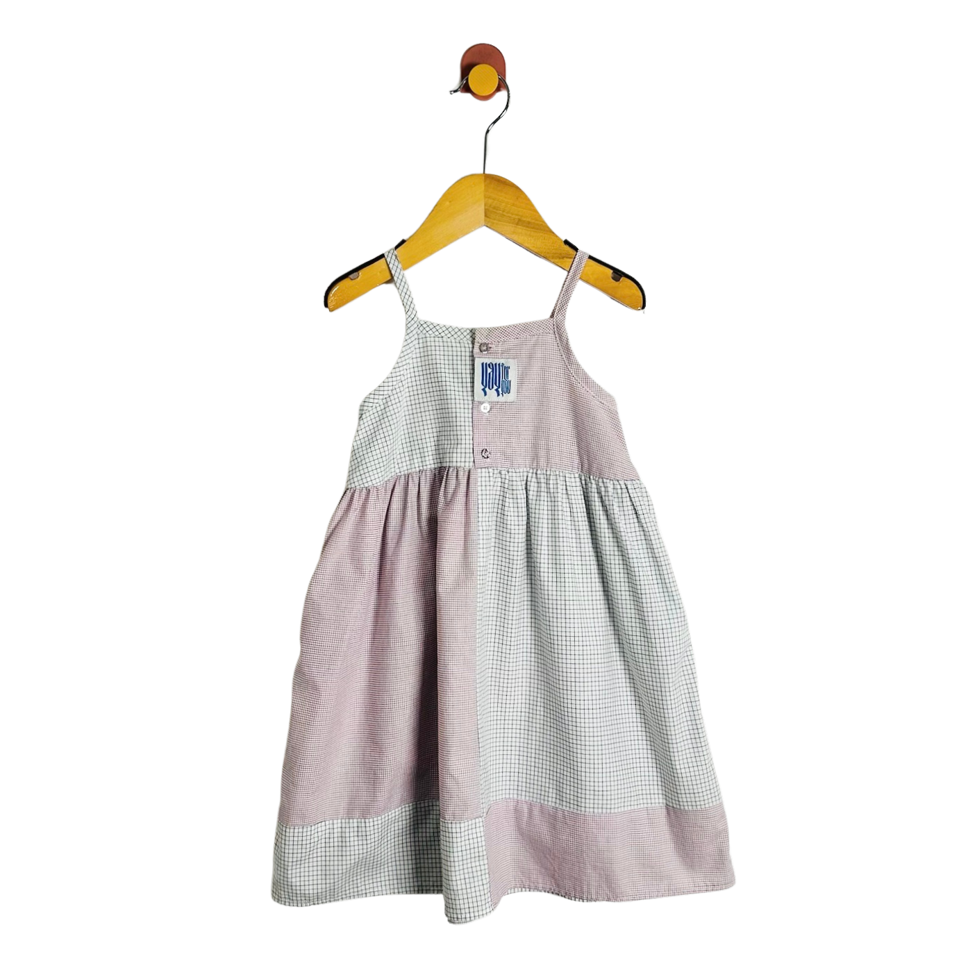 A baby girl's sleeveless dress with a dusty pink and white gingham patchwork design, hanging on a wooden hanger against a white background.