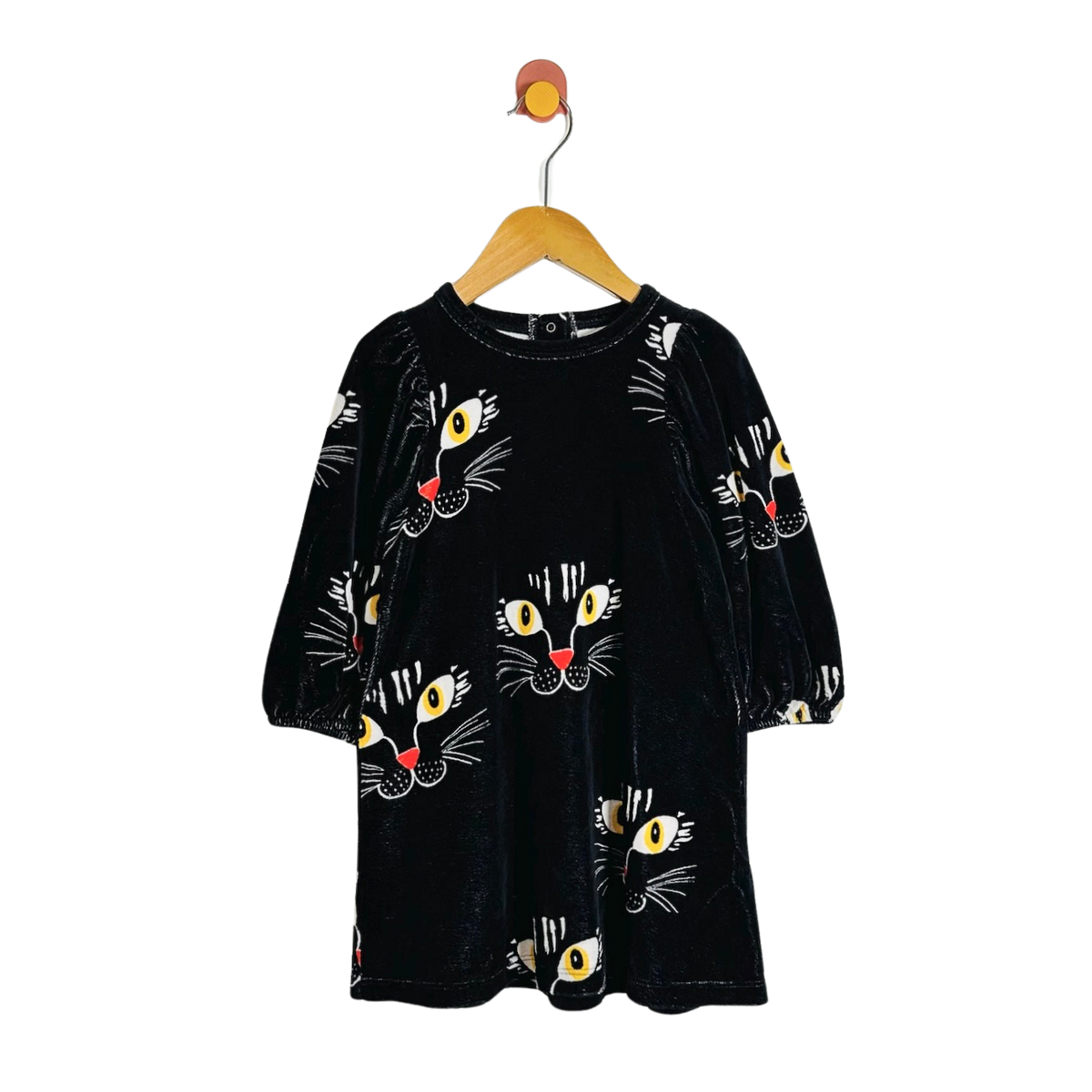 A black velvet long-sleeve dress with an all-over cartoon cat face print, hanging on a wooden hanger against a plain white background.