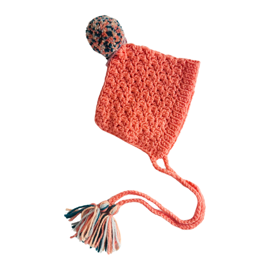 Crocheted pink hat with a pom-pom on a white background