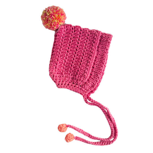 Pink knitted hat with a colorful pom-pom on a white background