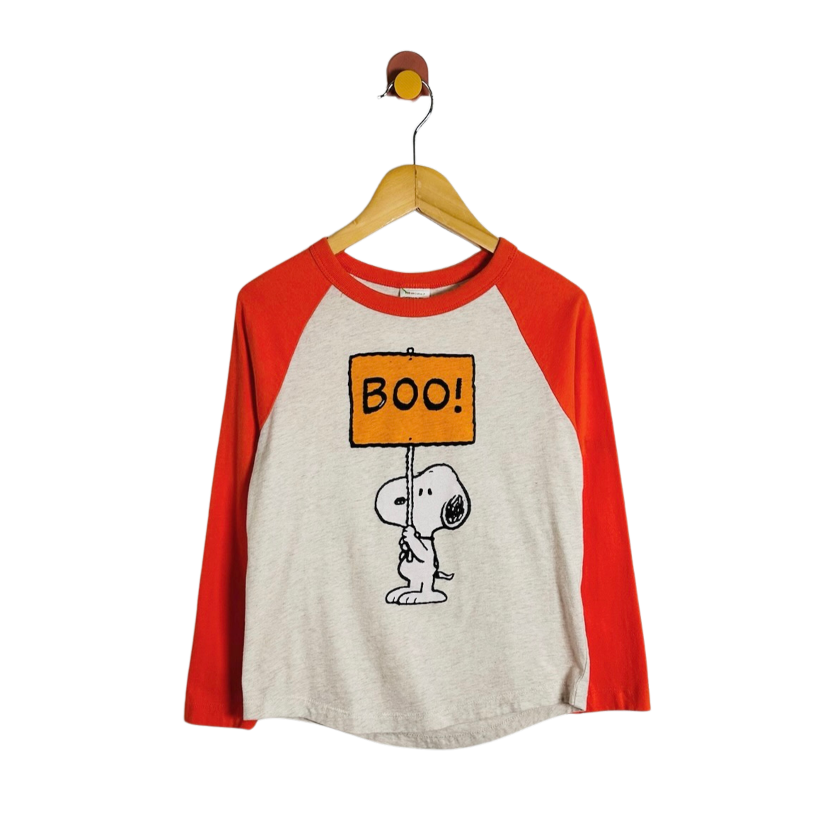A long-sleeve raglan t-shirt featuring a light heather gray body and bright red sleeves, with a graphic of Snoopy holding an orange sign that says 'BOO!'. The shirt is hanging on a wooden hanger with a small bird hook at the top, set against a plain white background.
