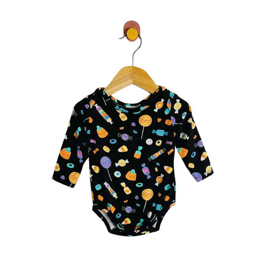 A baby long-sleeve bodysuit with a colorful candy print on a black background, hanging on a wooden hanger against a plain white background.