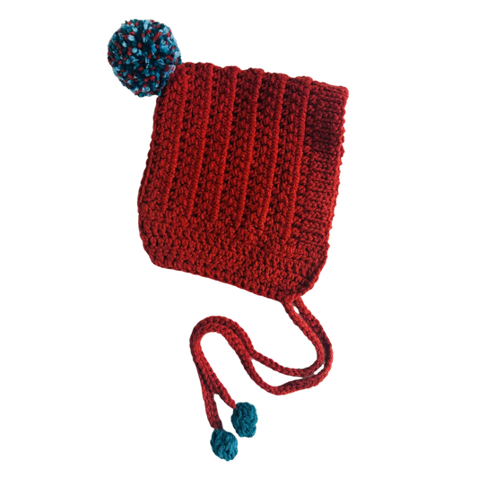 Red knitted hat with blue pom-poms on a white background
