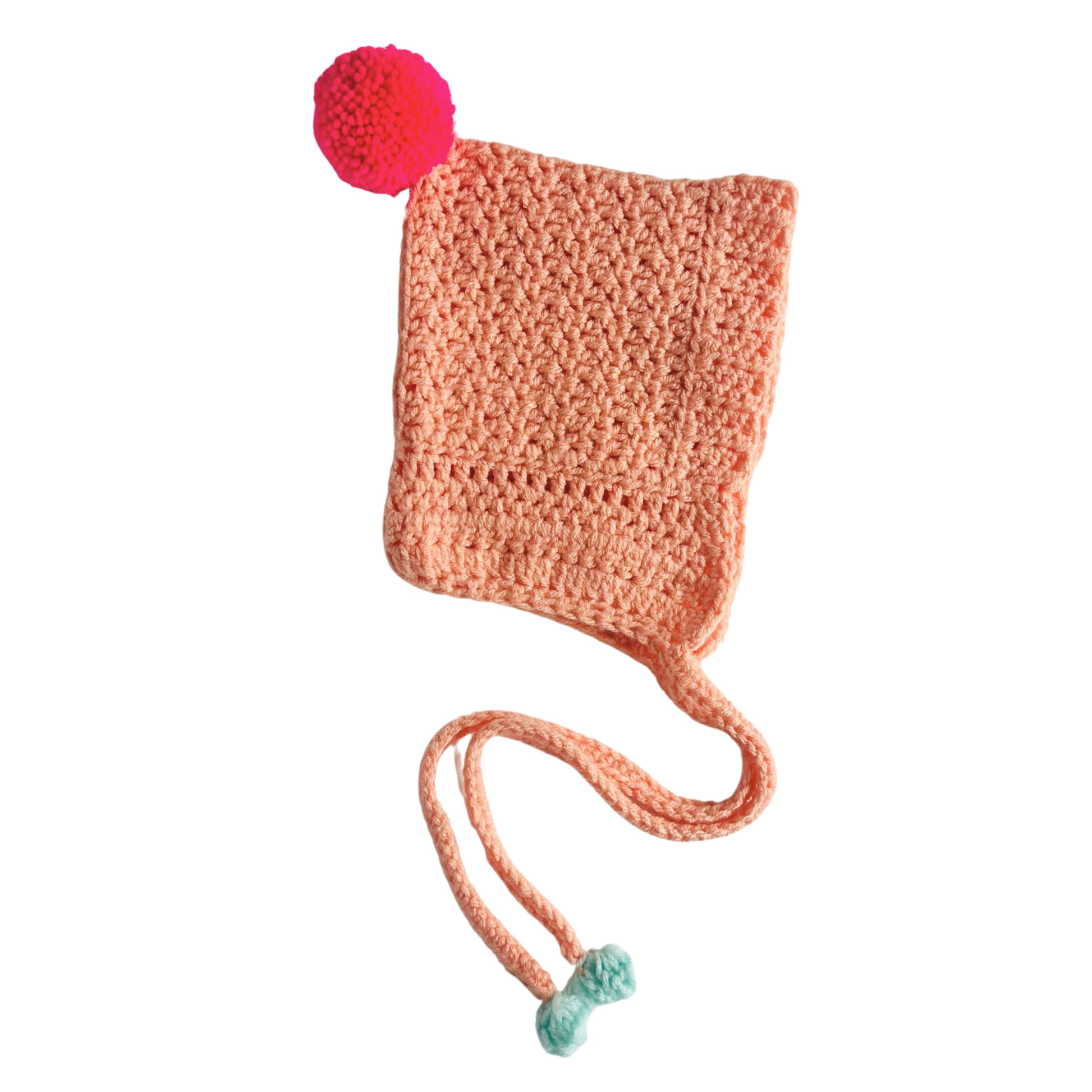 Crocheted peach-colored hat with a red pom-pom on a white background