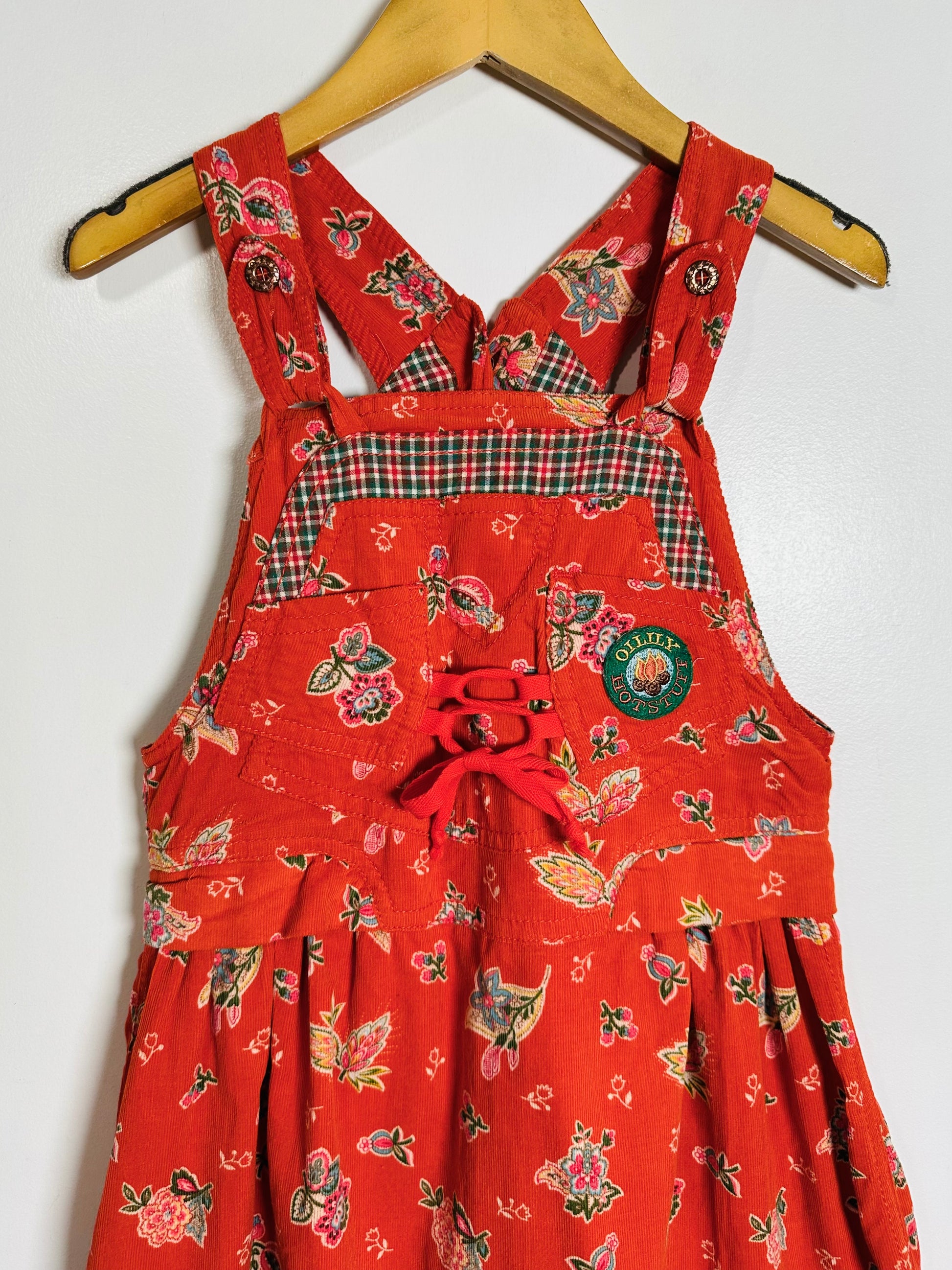 Red floral-patterned dress with plaid accents on a hanger against a white background