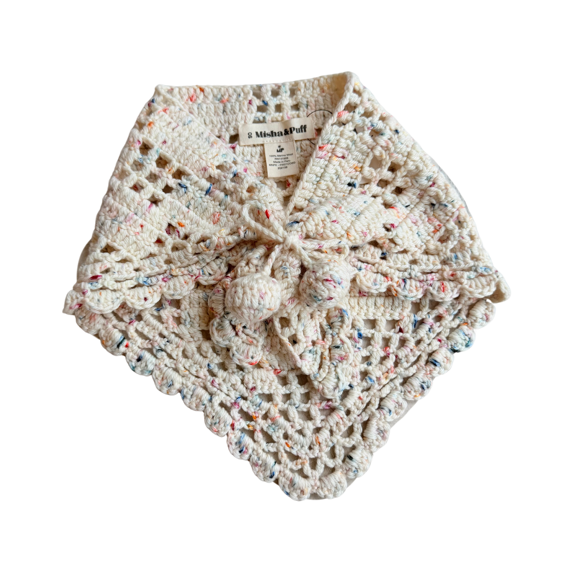 A handmade crochet baby wrap or bonnet in cream with multicolored flecks, featuring a knotted bow at the front and a scalloped edge, shown on a plain white background.