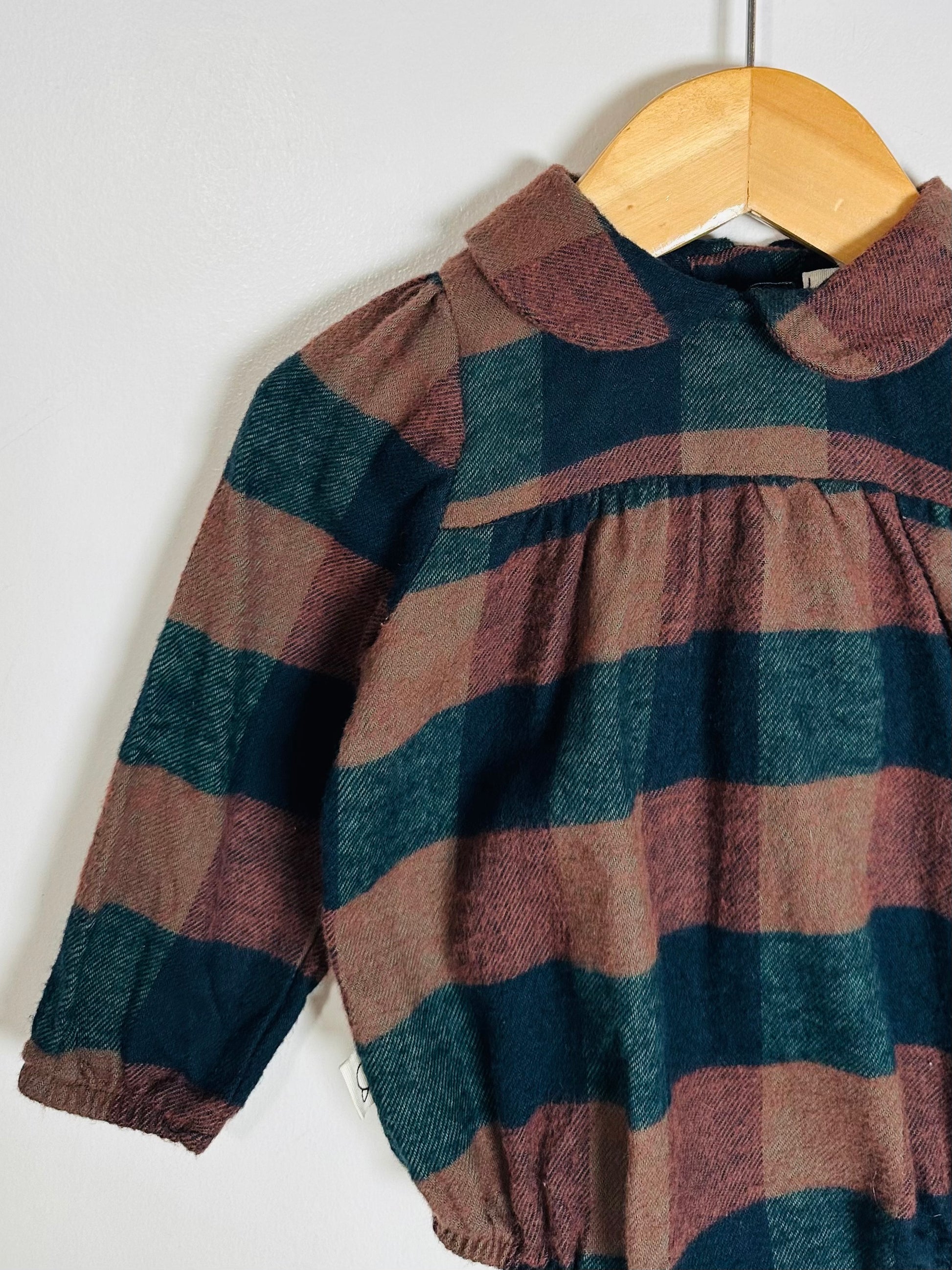 Plaid dress on a wooden hanger against a white background