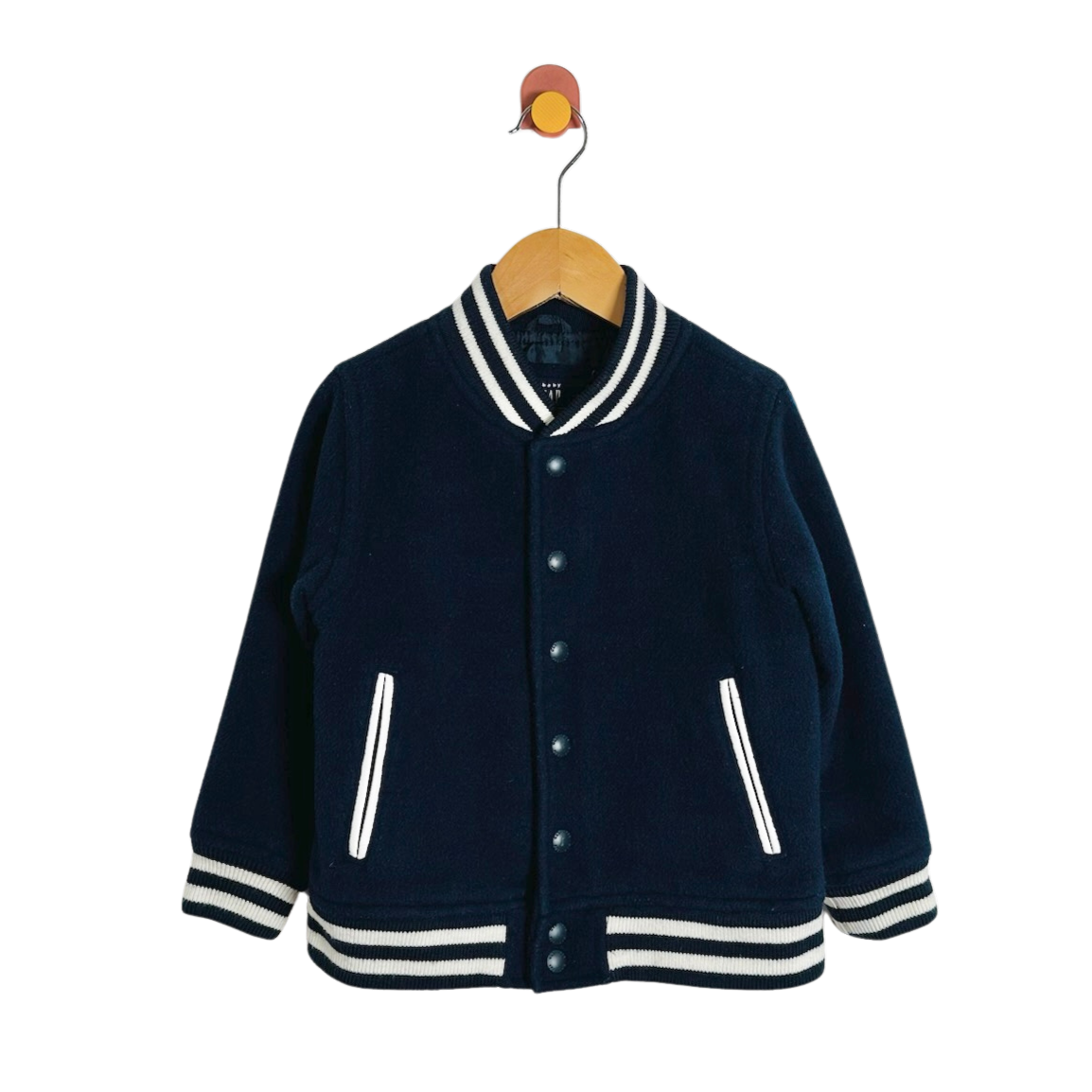 A navy blue knit varsity-style jacket with white striped trim on the collar, cuffs, and hem, hanging on a wooden hanger against a plain white background.