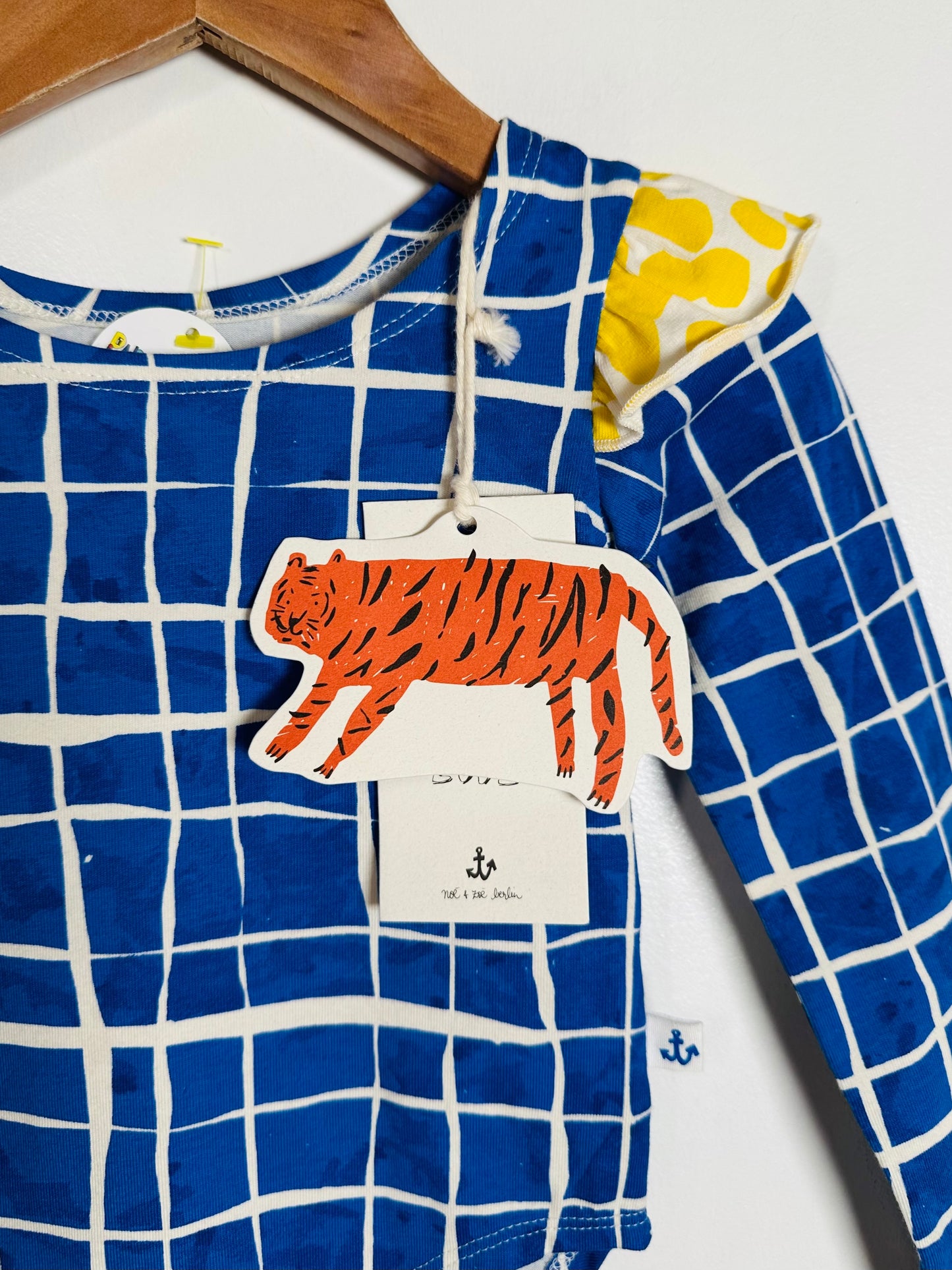 Children's blue and white checkered shirt with a tiger tag on a wooden hanger.