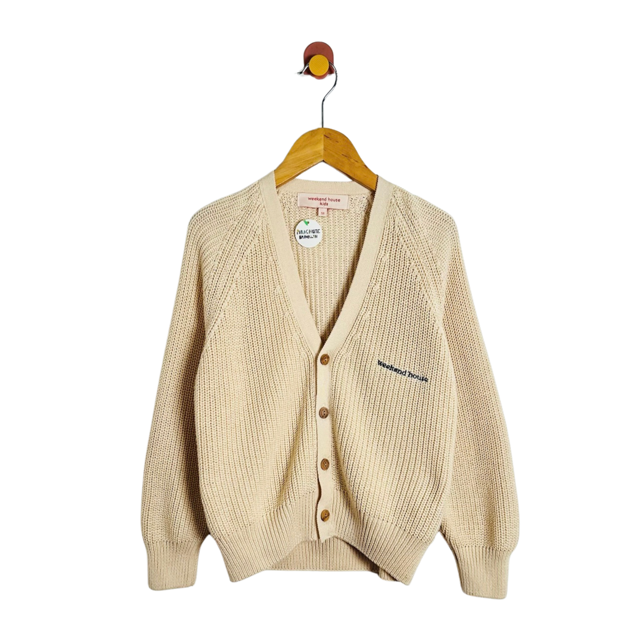 A cream-colored ribbed knit cardigan sweater hanging on a wooden hanger against a plain white background. The cardigan features a V-neck, brown buttons, and a small embroidered brand name on the left chest.