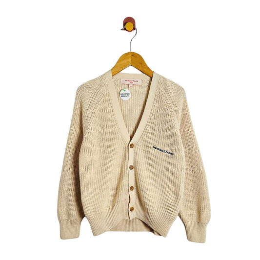 A cream-colored ribbed knit cardigan sweater hanging on a wooden hanger against a plain white background. The cardigan features a V-neck, brown buttons, and a small embroidered brand name on the left chest.
