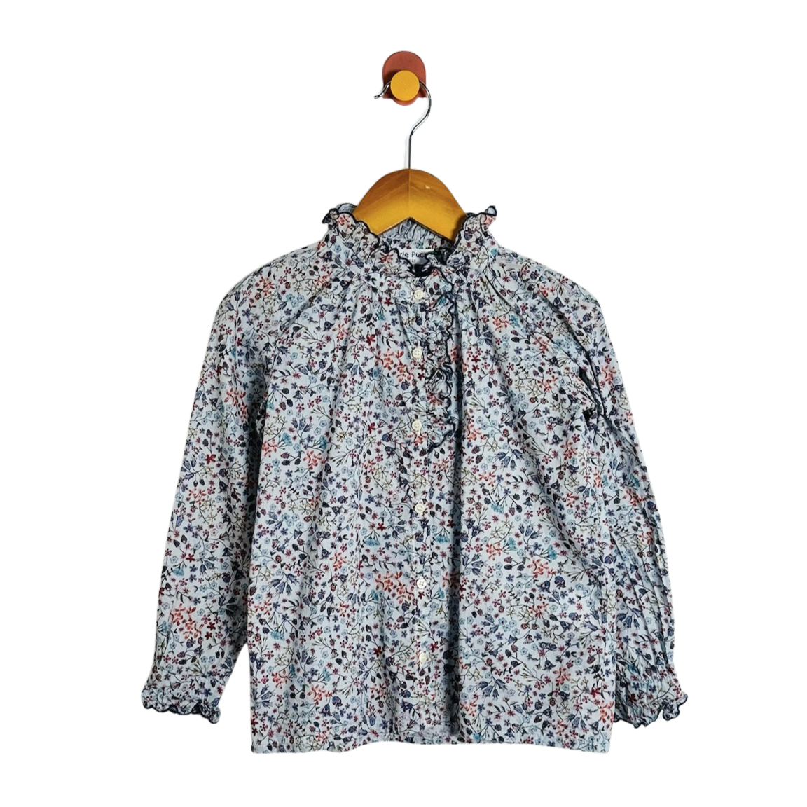 A long-sleeve blouse with a dense small floral print in muted blue, red, and black on a light gray base, hanging on a wooden hanger against a plain white background.