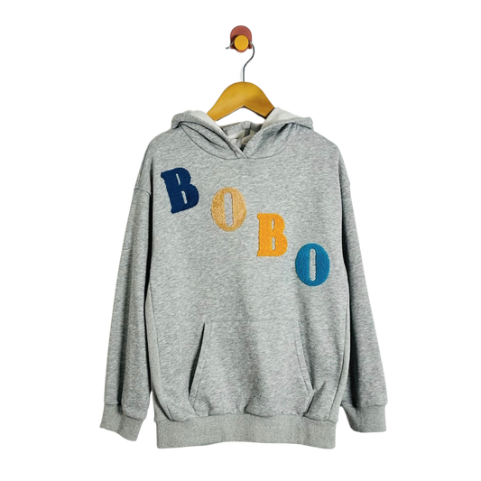A heather gray pullover hoodie hanging on a wooden hanger against a plain white background. The hoodie features the word 'BOBO' embroidered across the chest in alternating blue, yellow, and blue lettering.