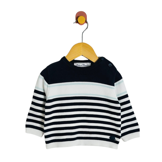 A baby knit sweater with horizontal navy and white stripes, hanging on a wooden hanger against a plain white background.