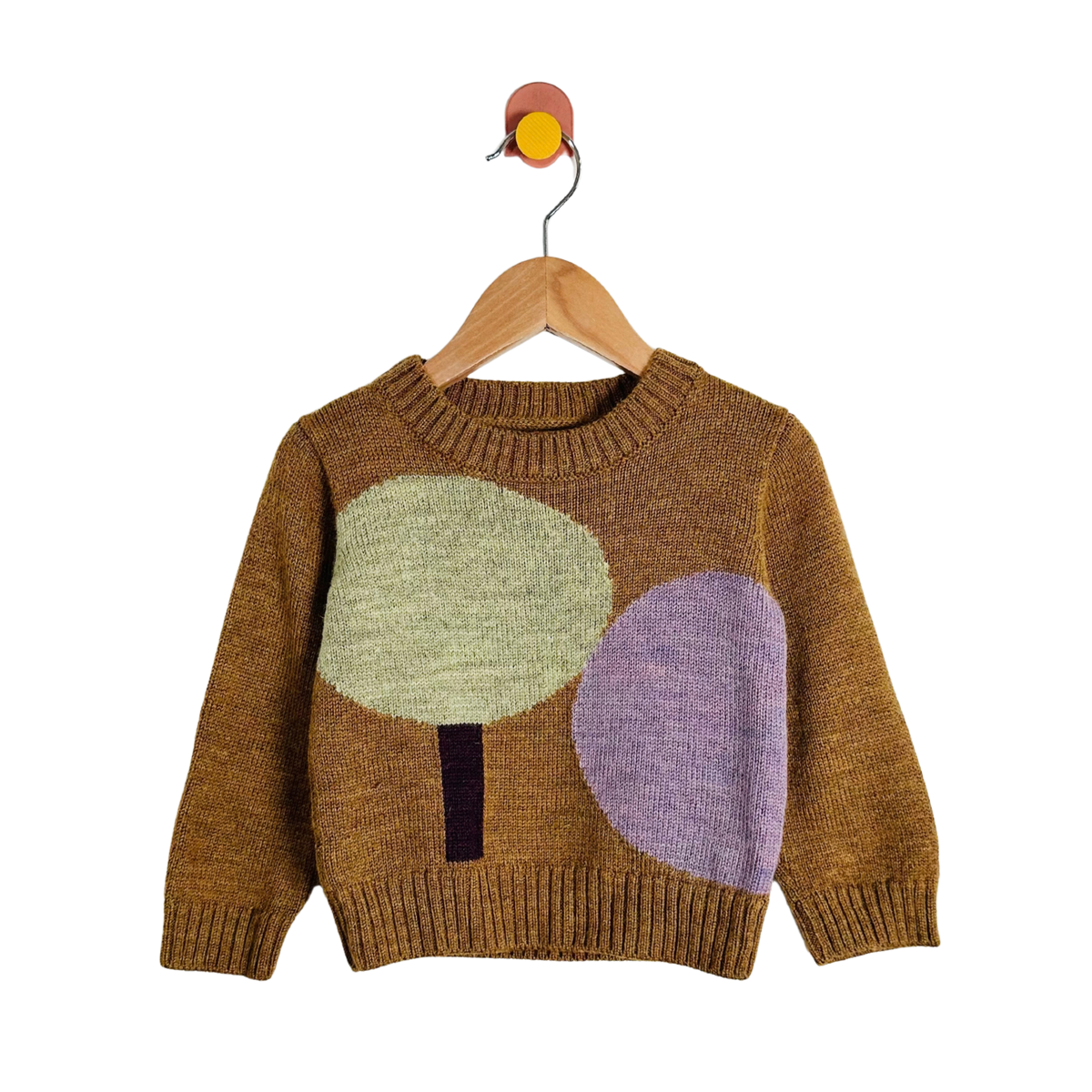 A knit baby sweater in a warm brown color, featuring two large abstract tree motifs in light green and lavender purple on the front, hanging on a wooden hanger against a white background.