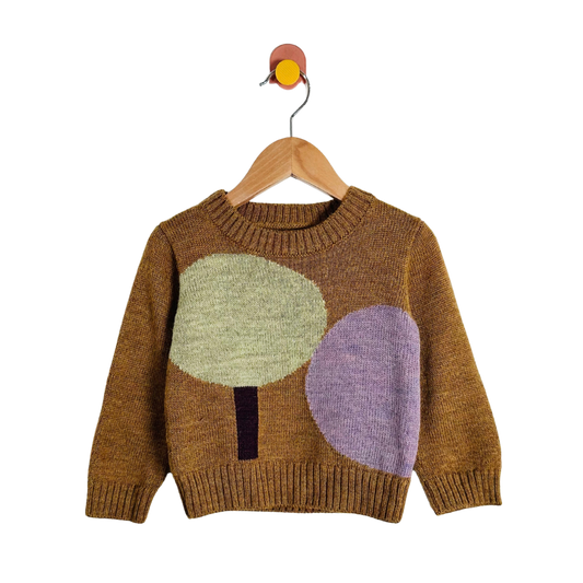A knit baby sweater in a warm brown color, featuring two large abstract tree motifs in light green and lavender purple on the front, hanging on a wooden hanger against a white background.
