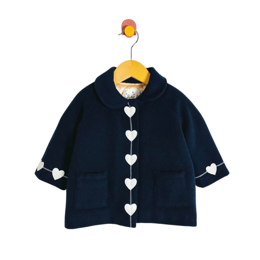 Navy blue children's coat with heart patterns on a hanger against a white background