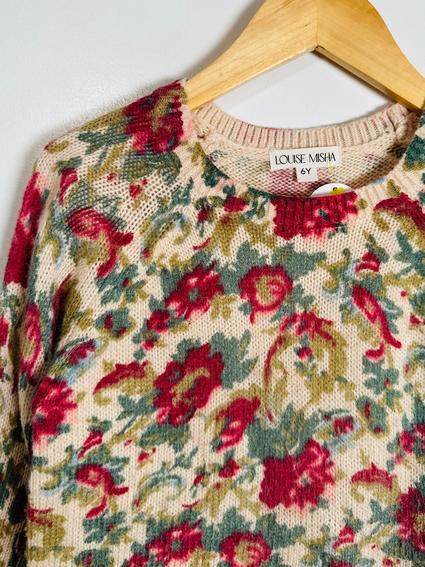 Floral patterned sweater on a hanger with 'Louise Misha' label.