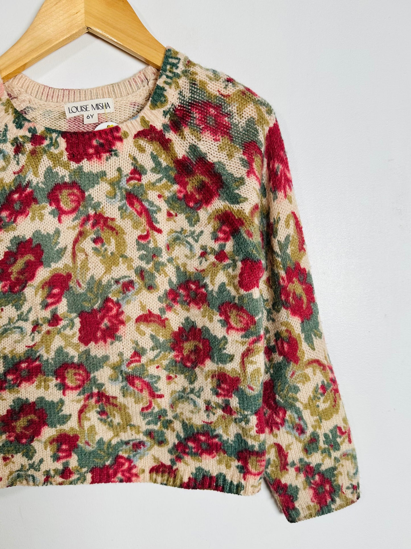 Floral patterned sweater on a hanger against a white background