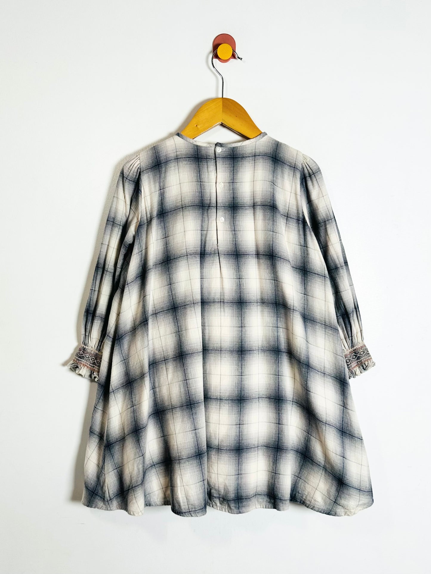 Plaid dress on a hanger against a white background