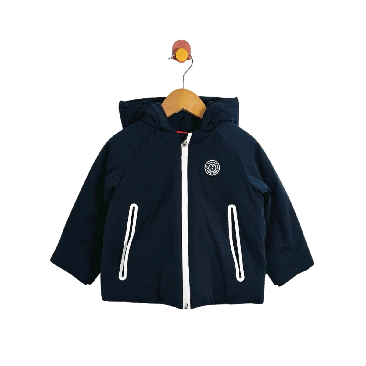 A navy blue hooded jacket with a white front zipper and white vertical zipper details on the pockets, hanging on a wooden hanger against a plain white background.