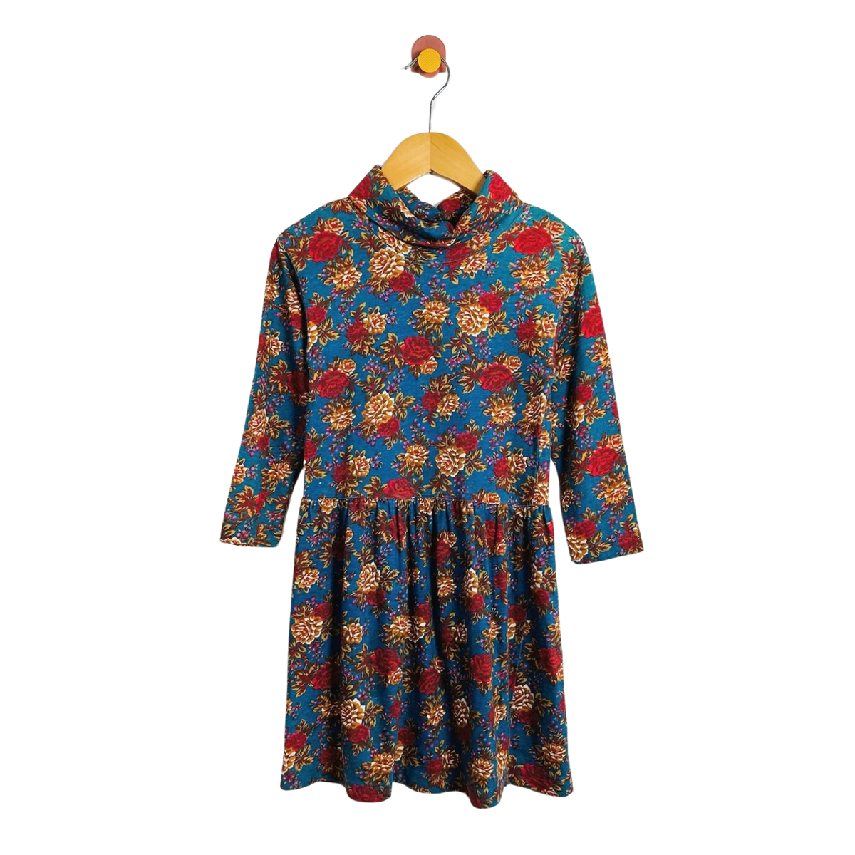 A long-sleeve cowl-neck dress with a vibrant floral print, hanging on a wooden hanger against a plain white background.