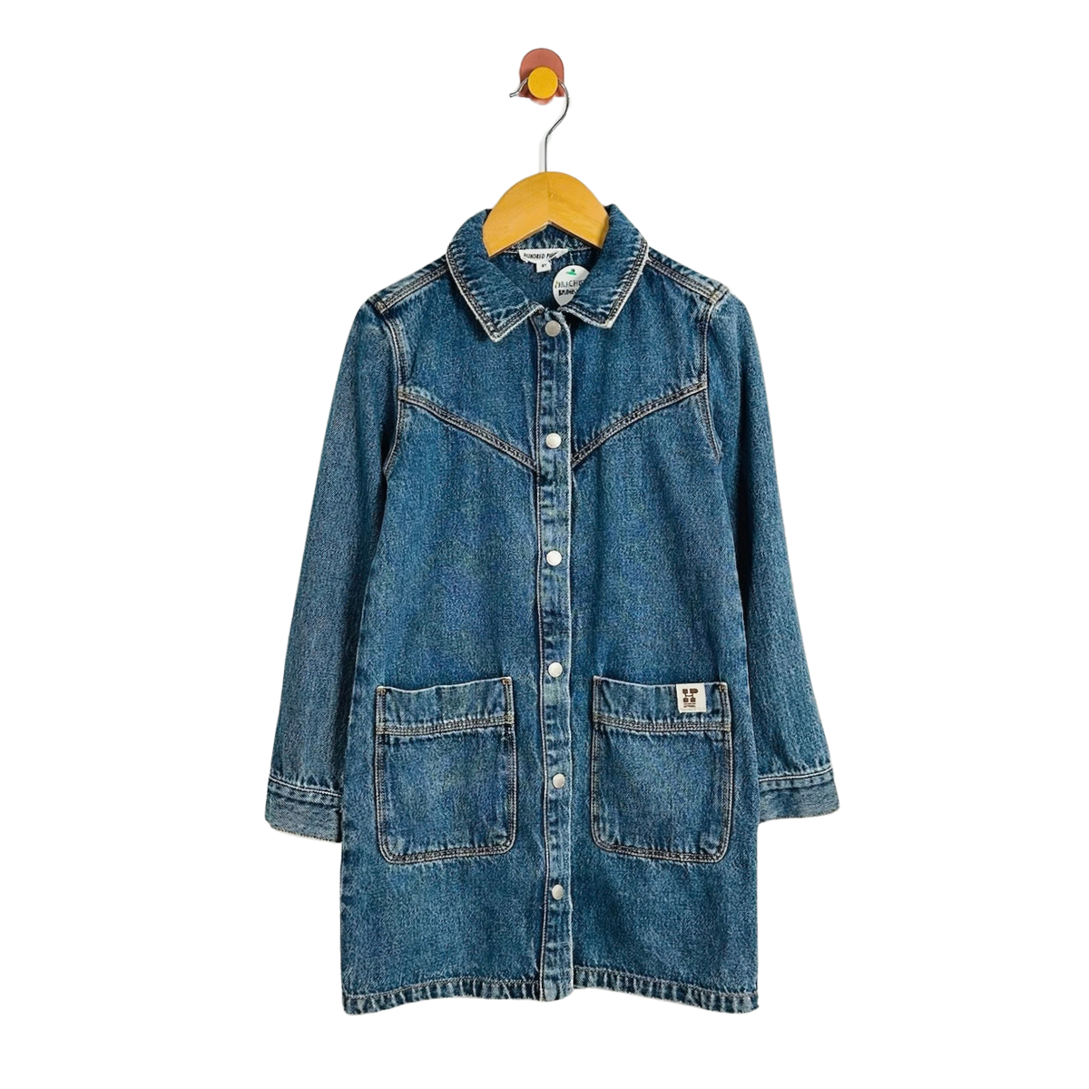 A blue denim shirt jacket with a western-style collar, button front, and two large front patch pockets, hanging on a wooden hanger against a plain white background.