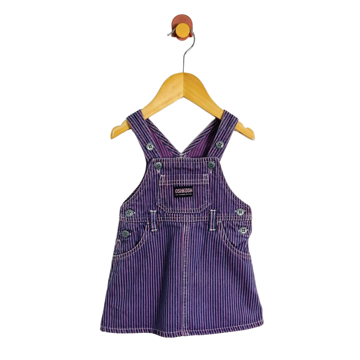 A baby/toddler purple denim overall dress with thin white vertical stripes, hanging on a wooden hanger against a plain white background.